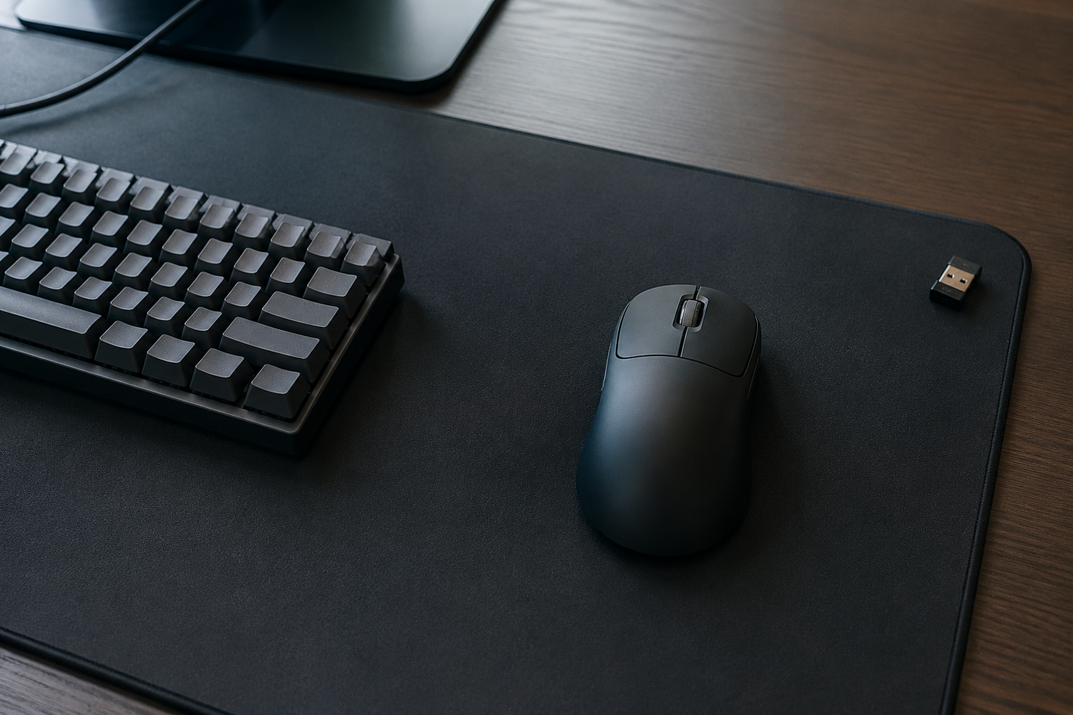 Black ultra-light wireless gaming mouse on a large mousepad beside a keyboard