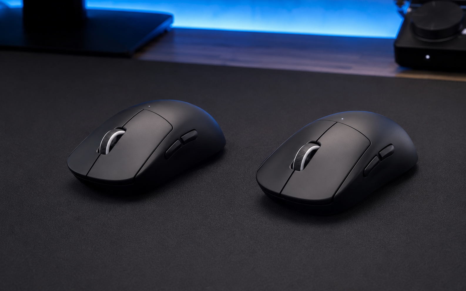 Two black ultra-light wireless gaming mice compared on a gaming desk